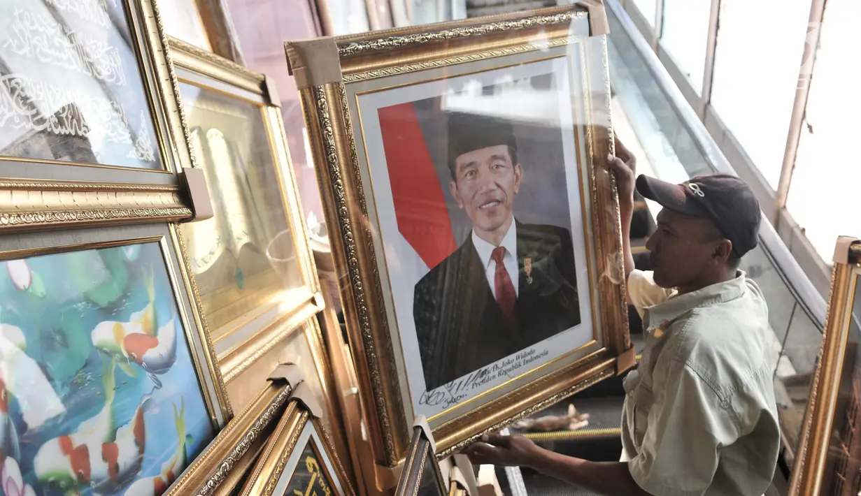 Pedagang merapikan foto Presiden-Wapres 2019-2024, Joko Widodo-KH Ma'ruf Amin di salah satu toko di Pasar Baru, Jakarta, Senin (26/8/2019). Meski belum resmi dilantik, foto Presiden dan Wakil Presiden Terpilih Joko Widodo-KH Ma'ruf Amin telah beredar di pasaran. (merdeka.com/Iqbal S. Nugroho)