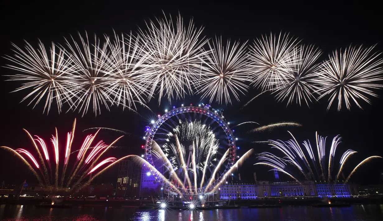 Kembang api meledak di atas kincir London Eye Ferris di Sungai Thames di London, untuk menandai awal tahun baru, Rabu (1/1/2020). (AP Photo/Matt Dunham)