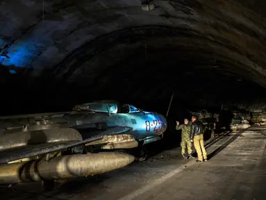 Tentara Albania berjalan di sebelah pesawat tempur MIG-19 dalam terowongan utama Pangkalan Udara Gjader di dekat Kota Lezhe, 5 Februari 2019. Pangkalan Udara Gjader berlokasi dalam perut gunung tandus. (Gent Shkullaku/AFP)