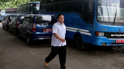 Seorang pria berjalan dekat deretan mobil dan bus dinas yang terparkir di area belakang Gedung DPR/MPR, Jakarta, Selasa (5/12). Mobil-mobil berplat merah itu dibiarkan mangkrak hingga berkarat lantaran menunggu proses lelang. (Liputan6.com/Johan Tallo)