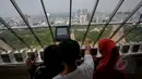 Pengunjung melihat Jakarta dari ketinggian puncak Monumen Nasional (Monas), Jakarta, Kamis (14/5/2015). Jumlah pengunjung mengalami peningkatan tinggi bertepatan libur kenaikan Isa Almasih. (Liputan6.com/Faizal Fanani)