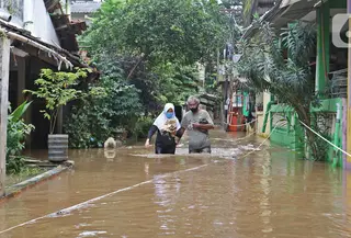 Warga berjalan melintasi banjir yang merendam kawasan Cipinang Melayu, Jakarta Timur, Jumat (19/2/2021). Banjir di kawasan tersebut akibat curah hujan yang tinggi dan meluapnya air dari Kali Sunter. (Liputan6.com/Herman Zakharia)