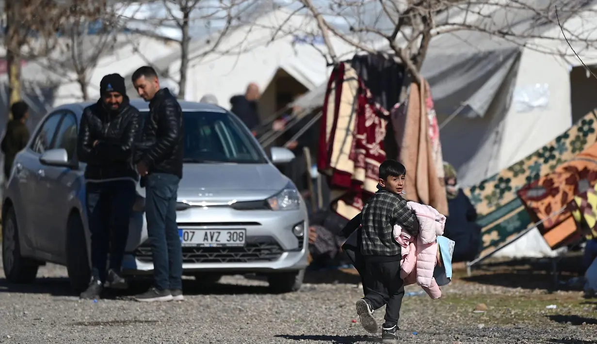 Seorang anak berjalan di sekitar kamp pengungsi Suriah yang didirikan oleh lembaga bantuan Turki AFAD di distrik Islahiye, Gaziantep, Turki, Rabu (15/2/2023). Gempa berkekuatan 7,8 magnitudo melanda Turki dan Suriah pada Senin (6/2), pusat gempa berada sekitar 26 km sebelah timur Kota Nurdagi di Turki pada kedalaman sekitar 18 km di Patahan Anatolia Timur.  (OZAN KOSE/AFP)