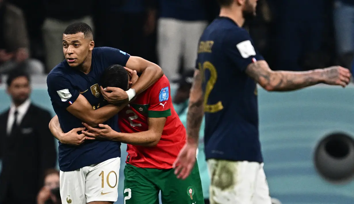 Penyerang Prancis #10 Kylian Mbappe menghibur bek Maroko #02 Achraf Hakimi pada akhir babak semifinal Piala Dunia 2022 di Al Bayt Stadium, Kamis (15/12/2022) dini hari WIB. Warganet di media sosial ramai mengomentari momen bromance Mbappe dan Hakimi ini. (Photo by GABRIEL BOUYS / AFP)