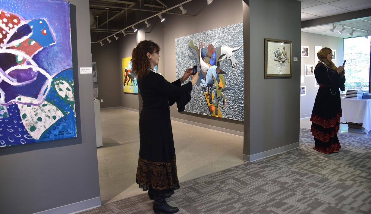 Pengunjung mengambil gambar koleksi museum tentang Palestina pada pembukaannya di Woodbridge, AS, Minggu (22/4). Museum ini menampilkan sejarah, seni, dan budaya Palestina dalam bentuk lukisan, sastra, fotografi dan barang bersejarah. (AFP/HECTOR RETAMAL)