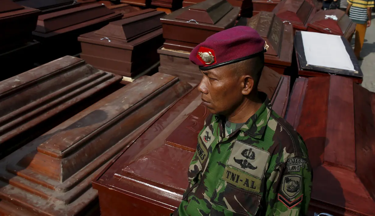 Anggota TNI berdiri di samping peti mati yang menjadi korban dari jatuhnya pesawat Hercules C-130 di Medan, Rabu (1/7/2015). Peristiwa ini menambah catatan kecelakaan yang disebabkan tuanya alustista yang digunakan TNI. (REUTERS/Beawiharta)
