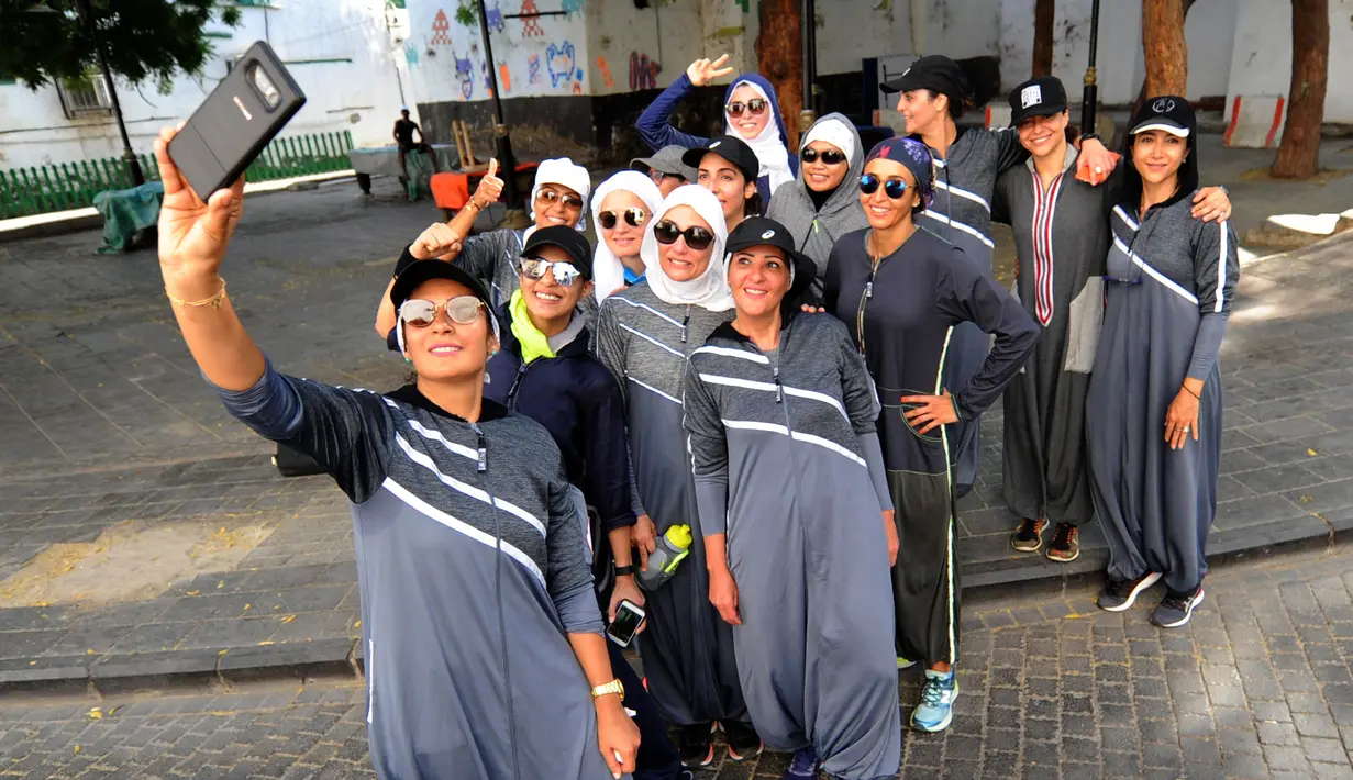 Perempuan Arab Saudi berswafoto saat jogging memperingati Women's Day atau Hari Perempuan Internasional di jalanan Distrik Al-Balad, Jeddah, Kamis (8/3). Sejak Mohammed bin Salman menjadi Putra Mahkota, dia memodernisasi negerinya. (Amer HILABI/AFP)