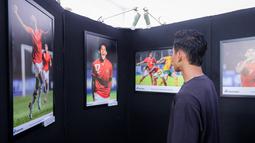 Pemain Timnas Indonesia, Rizky Ridho sedang melihat sejumlah karya foto bertema "Timnas Indonesia dari Masa ke Masa" saat pameran foto Media Cup 2025 di Cibis, Cilandak, Jakarta Selatan, Selasa (28/10/2025). (Bola.com/Bagaskara Lazuardi)