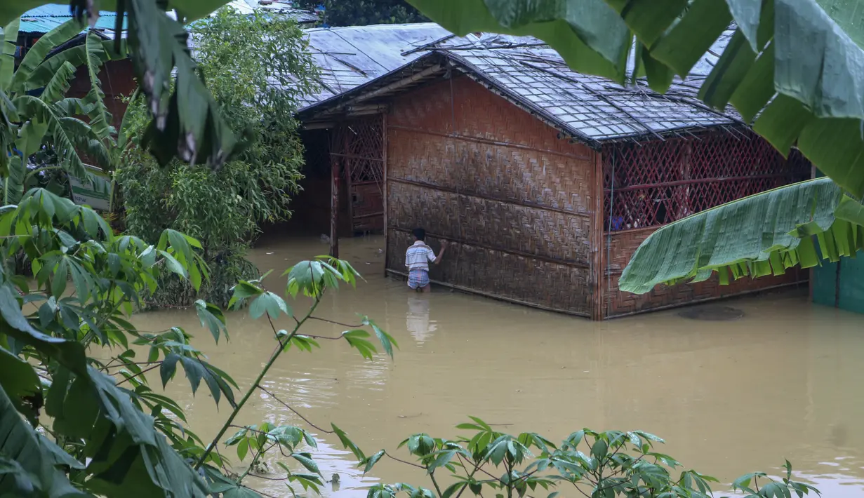 Seorang pengungsi Rohingya berjalan melewati banjir setelah hujan deras di kamp pengungsi Rohingya di Kutupalong, Bangladesh (28/7/2021). (AP Photo/ Shafiqur Rahman)
