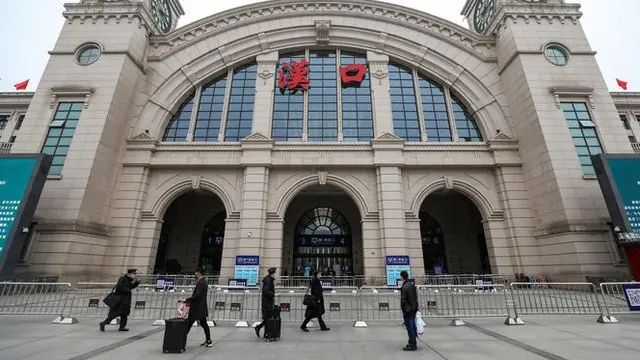 Orang-orang berjalan melewati Stasiun Kereta Api Hankou yang ditutup di Wuhan, Provinsi Hubei, China, Kamis (23/1/2020). Pemerintah China mengisolasi Kota Wuhan yang berpenduduk sekitar 11 juta jiwa untuk menahan penyebaran virus corona.