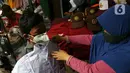 Pembeli mencoba seragam sekolah untuk anaknya di Pasar Mester, Jakarta , Minggu (29/8/2021). Menurut pedagang, penjualan seragam sekolah kembali meningkat hingga 30 persen jelang masuk sekolah tatap muka yang dilaksanakan kembali pada 30 Agustus 2021. (Liputan6.com/Herman Zakharia)