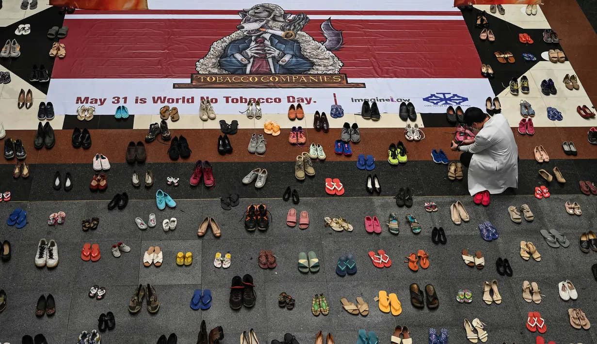 Seorang dokter mengambil foto instalasi seni dengan 321 pasang sepatu yang menandakan kematian akibat merokok dalam rangka memperingati Hari Tanpa Tembakau Sedunia di Pusat Paru Filipina, Quezon City, pinggiran kota Manila, Filipina, Selasa (31/5/2022). (JAM STA ROSA/AFP)