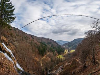 Panorama dari 27 foto yang diambil pada 3 Maret 2023 menunjukkan jembatan gantung yang sedang dibangun, menghadap ke air terjun di Todtnau, barat daya Jerman. Pembangunan jembatan sepanjang 450 meter yang digantung dengan ketinggian hingga 120 meter ini diharapkan selesai pada Mei 2023 dan menjadi daya tarik wisata utama di Black Forest. (PATRICK HERTZOG / AFP)