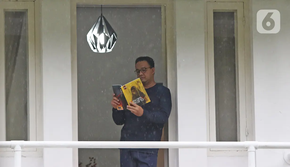 Gubernur DKI Jakarta Anies Baswedan saat melihat buku foto Rekam Jakarta 2020 di balkon rumah dinas, Jakarta, Kamis (3/12/2020). Usai terkonfirmasi positif Covid-19, Anies Baswedan melakukan isolasi mandiri di rumah dinas gubernur selama 14 hari ke depan. (Liputan6.com/Herman Zakharia)