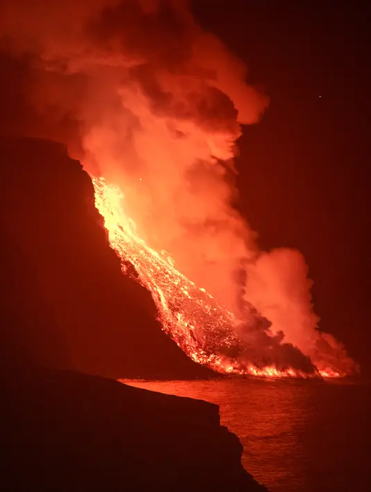 Lava dari gunung berapi mencapai laut di pulau Canary La Palma, Spanyol, Rabu (29/9/2021) dinihari. Lava merah panas dari gunung berapi Cumbre Vieja mencapai Samudra Atlantik, sembilan hari setelah mulai mengalir menuruni gunung. (AP Photo/Saul Santos)