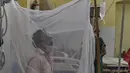 Seorang pasien duduk di bawah kelambu di bangsal demam berdarah sebuah rumah sakit pemerintah di Allahabad, India (30/8/2021). (AFP/Sanjay Kanojia)