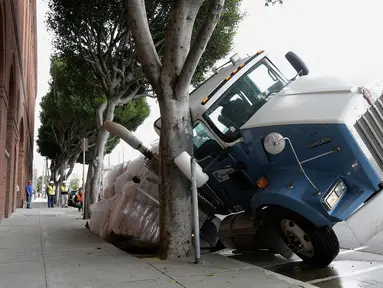 Sebuah truk terjebak di sebuah saluran pembuangan di San Francisco, AS, Jumat (5/5). Diduga karena muatan yang terlalu berat membuat bagian atas saluran pembuangan menjadi amblas. (AP Photo / Jeff Chiu)