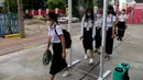 Para siswa yang mengenakan masker berjalan melalui gerbang yang dilengkapi dengan semprotan desinfektan ketika sekolah dibuka kembali di Phnom Penh, Senin (7/9/2020). Sekolah-sekolah di Kamboja dibuka kembali pada Senin (7/9) setelah enam bulan ditutup akibat COVID-19. (TANG CHHIN Sothy /AFP)