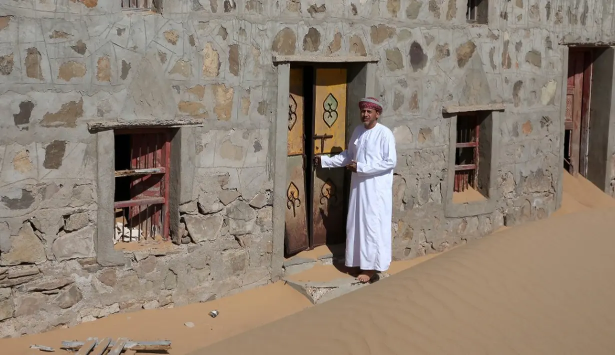 Mantan penduduk Wadi al-Murr, Mohammed al-Ghanbousi berdiri di samping rumahnya yang ditinggalkan di Desa Omani, Wadi al-Murr, Oman, 31 Desember 2020. Penduduk Wadi al-Murr  yang meninggalkan desanya meningkatkan jumlah mereka yang bermigrasi ke kota-kota. (MOHAMMED MAHJOUB/AFP)