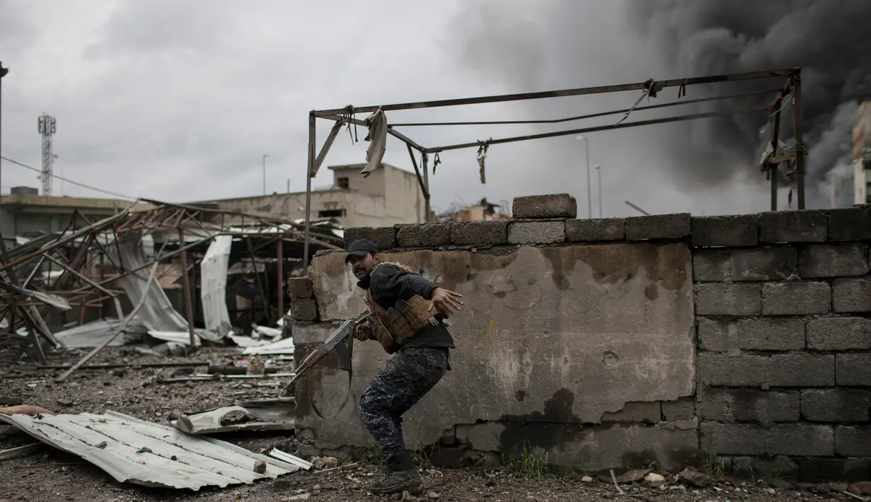Polisi Irak mencari perlindungan saat bertempur melawan militan ISIS di barat Mosul, Irak, 16 Maret 2017. (AP Photo/Felipe Dana)