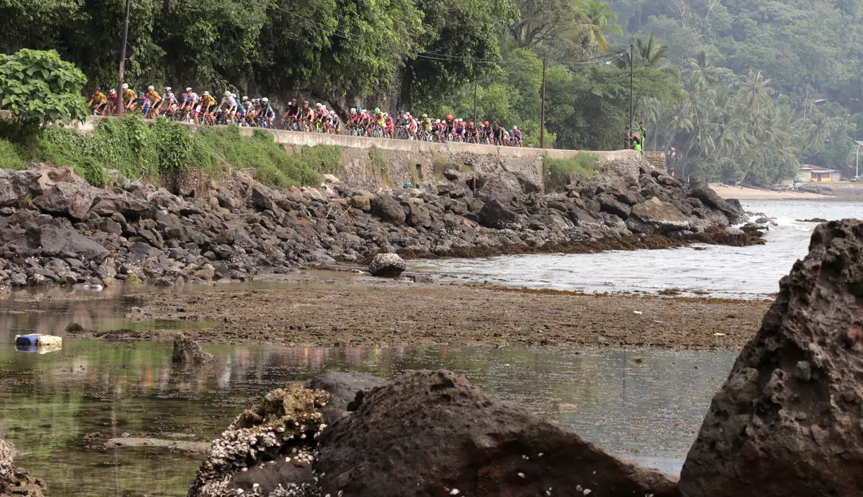 Para pebalap sepeda melintasi Pantai Teluk Bayur dalam Etape 1 Tour de Singkarak antara Painan, Kabupaten Pesisir Selatan menuju Pariaman, Sumatra Barat saat, Sabtu (3/10/2015). (Bola.com/Arief Bagus)