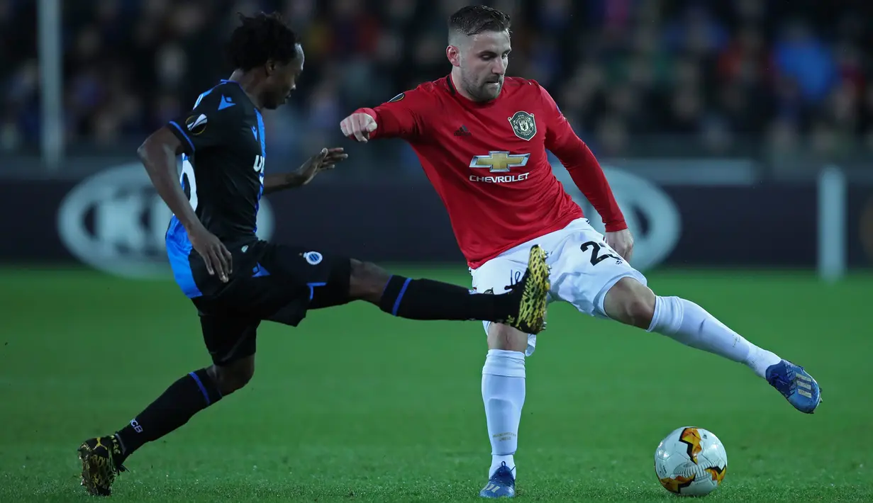 Bek Manchester United, Luke Shaw, berebut bola dengan pemain Club Brugge, Percy Tau dalam leg pertama babak 32 besar Liga Europa di Jan Breydelstadion, Kamis (20/2/2020). Manchester United gagal meraih hasil maksimal usai ditahan imbang Club Brugge 1-1. (AP/Francisco Seco)