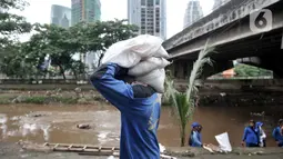 Pekerja Sudin SDA Jakpus membawa karung berisi pasir untuk penutupan titik-titik lubang rembesan di Tanggul Kanal Banjir Barat, Latuharhari, Minggu (5/1/2020). Proses penutupan cara menutup lubang rembesan dengan coran yang berisi campuran semen, pasir dan batu. (merdeka.com/Iqbal Nugroho)