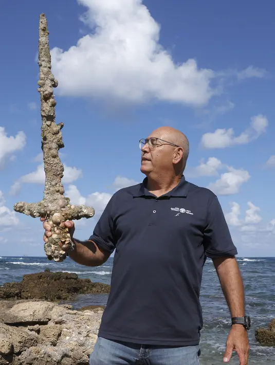 Jacob Sharvit dari Israel Antiquities Authority memperlihatkan pedang berusia 900 tahun yang diyakini milik seorang tentara salib di Caesarea pada 19 Oktober 2021. Seorang penyelam amatir menemukan pedang tersebut dari dasar laut Mediterania.  (JACK GUEZ / AFP)