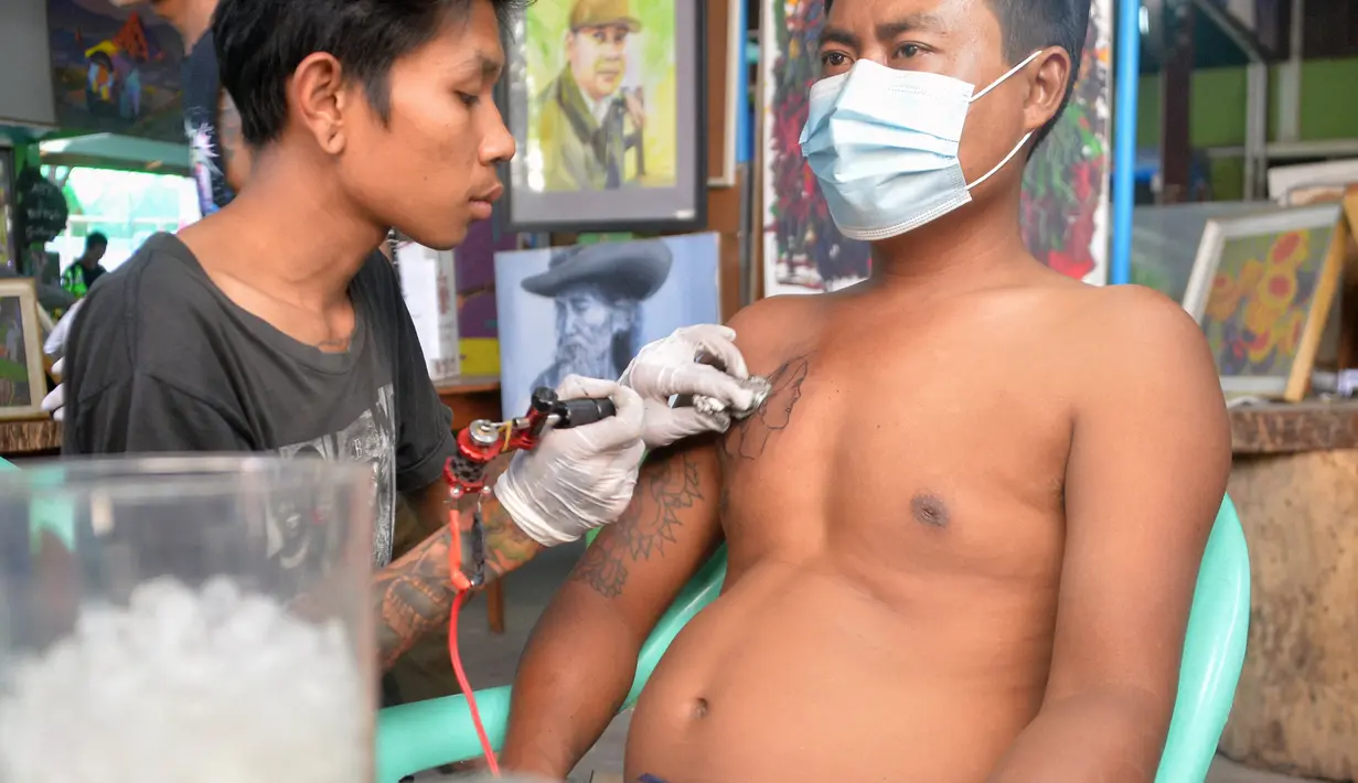 Seorang pria membuat tato bergambar pemimpin Myanmar yang ditahan Aung San Suu Kyi sebagai protes atas kudeta militer di sebuah salon tato di Naypyidaw, Rabu (10/2/2021). Warga Myanmar terus mengekspresikan perlawanan terhadap kudeta militer, salah satunya menyuarakan aspirasi lewat tato. (STR/AFP)