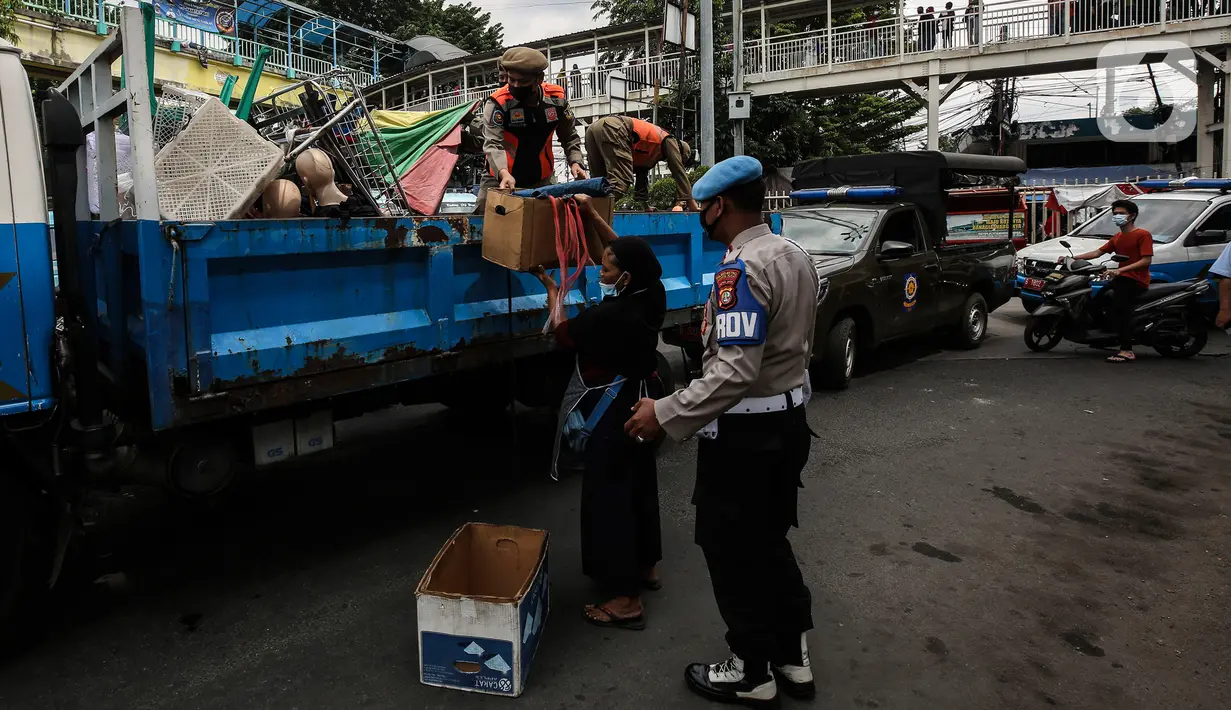 Aparat gabungan mengangkut dagangan pedagang yang berjualan di trotoar di kawasan Tanah Abang, Jakarta, Minggu (2/5/2021). Selain merazia barang dagangan pedagang, aparat gabungan juga menegur warga yang tidak menerapkan protokol kesehatan. (Liputan6.com/Johan Tallo)