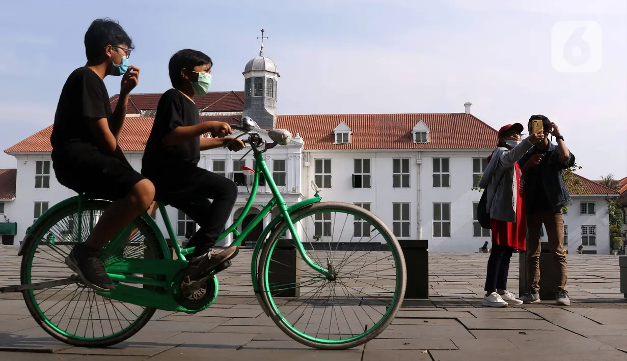 Anak-anak mengenakan masker menggunakan sepeda wisata di kawasan Kota Tua Jakarta, Kamis (29/10/2020). Libur panjang di masa pemberlakuan PSBB transisi Jakarta dimanfaatkan warga untuk mengunjungi lokasi-lokasi wiisata. (Liputan6.com/Helmi Fithriansyah)