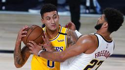 Pebasket Los Angeles Lakers, Kyle Kuzma, berusaha melewati pemain Denver Nuggets, Jamal Murray, pada laga NBA di The Arena, Senin (11/8/2020). LA Lakers menang dengan skor 124-121. (AP Photo/Ashley Landis, Pool)