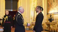 Pembalap Lewis Hamilton berbincang dengan Pangeran Charles setelah menerima gelar kebangsawanan dari Kerajaan Inggris di Kastil Windsor, Rabu (15/12/2021). (Dominic Lipinski/PA via AP)