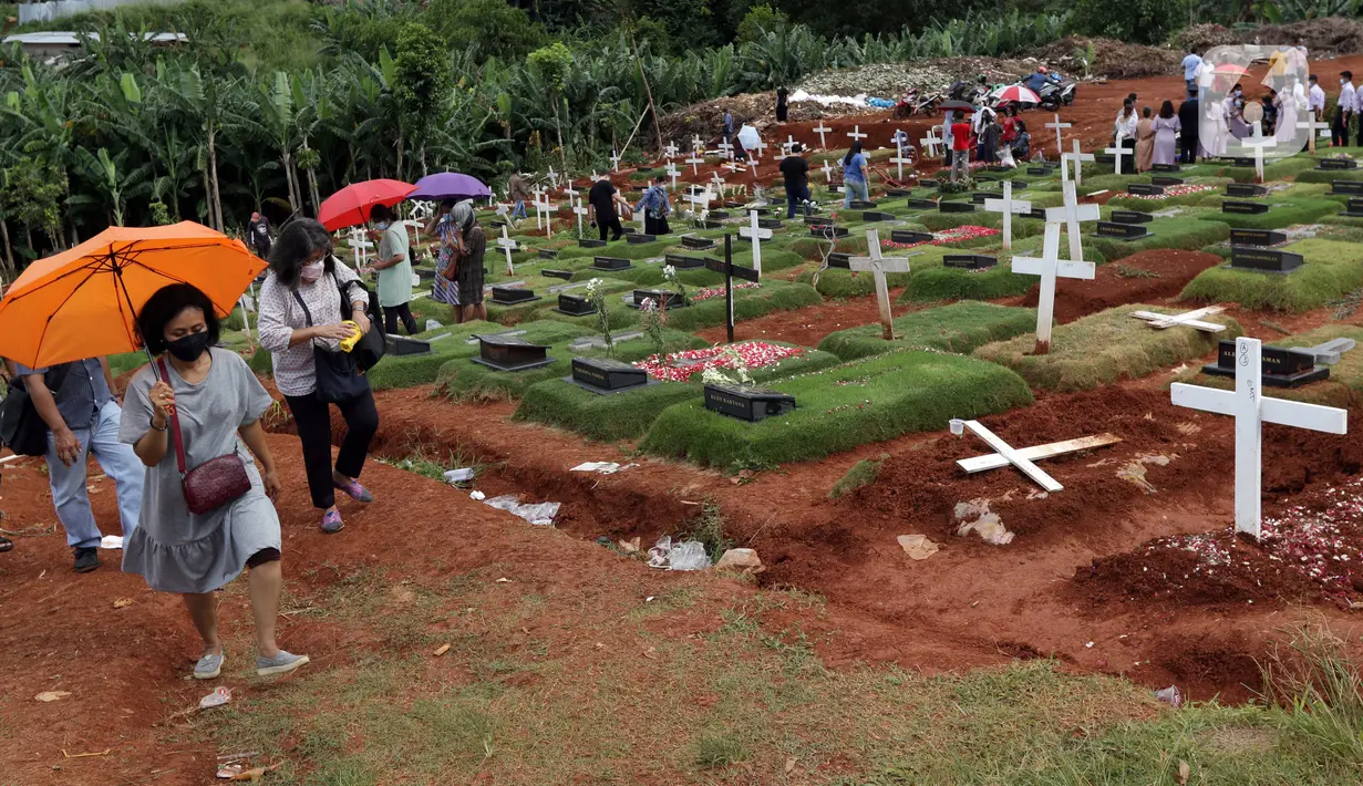 Warga berjalan meninggalkan area pemakaman khusus dengan protokol COVID-19 di TPU Pondok Ranggon, Jakarta, Jumat (25/12/2020). Momen perayaan Natal 2020 dimanfaatkan sejumlah umat kristiani untuk berziarah mendoakan kerabat yang dimakamkan dengan protokol COVID-19. (Liputan6.com/Helmi Fithriansyah)