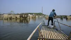 Seorang pria mengendalikan rakit bambunya di kawasan Bendungan Karian yang mengering di Kampung Somang, Lebak, Banten, Kamis (30/7/2026). (AFP/ Bay Ismoyo)