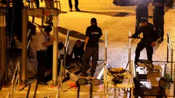 Polisi Israel menyingkirkan detektor logam di depan pintu masuk kompleks Masjid Al Aqsa di Kota Tua Yerusalem, Selasa (25/7) dini hari. Ketegangan menyebar cepat sejak Israel memasang detektor logam di pintu masuk area tersebut. (AP Photo/Mahmoud Illean)