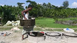 Seorang anak laki-laki Bangladesh membuat cetakan untuk pembuatan toilet di Sonarpara, Cox's Bazar, Rabu (11/10). Pekerja di pabrik pembuat toilet harus bekerja ekstra agar dapat memenuhi permintaan dari kamp pengungsian Rohingya. (INDRANIL MUKHERJEE/AFP)