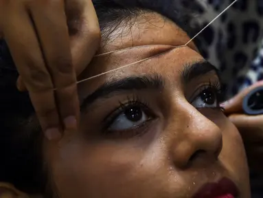 Seorang wanita Pakistan membersihkan rambut di wajah di salon kecantikan menjelang  Hari Raya Idul Fitri di Karachi (3/6/2019). Umat Muslim di seluruh dunia sedang bersiap untuk merayakan Hari Raya Idul Fitri, yang menandai akhir bulan puasa Ramadan. (AFP Photo/Asif Hassan)