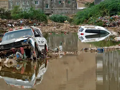 Mobil-mobil terjebak air berlumpur menyusul banjir yang disebabkan oleh Topan Shaheen di Mukalla, Provinsi Hadramaut, Yaman, Kamis (7/10/2021). Topan Shaheen yang melanda negara tetangga, Oman, mempengaruhi wilayah tersebut. (AFP)