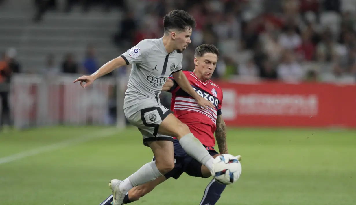 Gelandang Paris Saint-Germain (PSG) Vitinha berebut bola dengan gelandang Jonas Martin Lille pada pekan ketiga Ligue 1 (Liga Prancis) 2022/2023  di Stadion Pierre-Mauroy, Senin (22/8/2022) dini hari WIB.  PSG berpesta gol ke gawang Lille dengan skor 7-1. (AP Photo/Michel Spingler)
