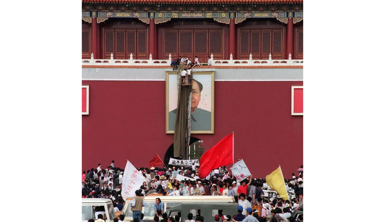 23 Mei 1989, beberapa orang tak dikenal terlihat berusaha mencabut gambar pemimpin Tiongkok, Mao Zedong di Lapangan Tiananmen, Tiongkok. (AFP PHOTO/CATHERINE Henriette)