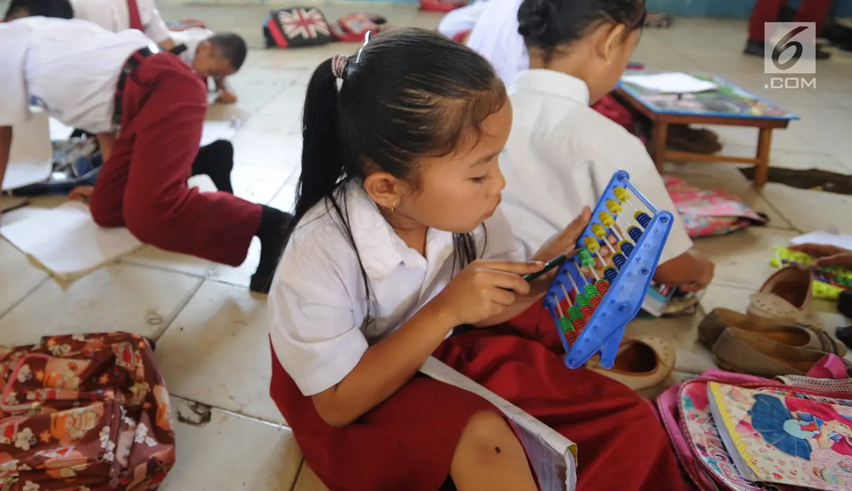 Seorang murid kelas II melakukan kegiatan belajar di lantai kelas SDN Kertajaya 2, Rumpin, Bogor, Senin (3/9). Tidak tersedianya meja dan kursi di tiga ruang kelas menyebabkan mereka belajar di lantai selama lebih dari 3 tahun. (Merdeka.com/Arie Basuki)