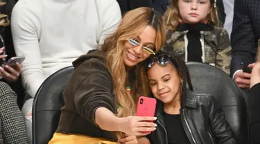 Penyanyi Beyonce dan putrinya Blue Ivy Carter berselfie saat menonton pertandingan NBA All-Star Game 2018 di Staples Center di Los Angeles, California, AS (18/2). (Allen Berezovsky/Getty Images/AFP)