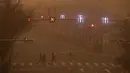 Orang-orang berjalan di seberang jalan saat ibu kota dilanda polusi udara dan badai pasir di Beijing, Senin (15/3/2021). (AP Photo/Andy Wong)