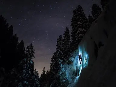 Anggota tim Arnica, Pierre mendaki tebing es saat sesi latihan malam hari di dekat La Lecherette, Hongrin, Kota Vaud, Swiss, Rabu (14/2). Pierre mendaki di bawah malam yang penuh bintang. (Anthony Anex/Keystone via AP)