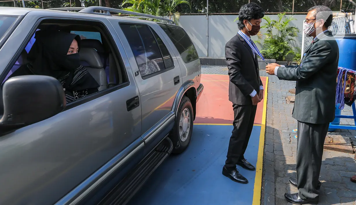 Kepala sekolah menyematkan medali kelulusan pada acara Wisuda Pelepasan Kelas XII di Madrasah Aliyah Annajah, Petukangan, Jakarta, Kamis (18/6/2020). Sebanyak 85 siswa mengikuti Wisuda Drive Thru guna mencegah penyebaran virus Covid-19. (Liputan6.com/Fery Pradolo)