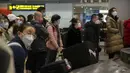 Pelancong yang memakai masker menunggu barang bawaan mereka di area kedatangan internasional di Bandara Internasional Ibukota Beijing di Beijing, Senin (9/1/2023). Pelancong internasional pertama tiba di China tanpa karantina wajib yang telah diberlakukan pada awal penerbangan. Pandemi tiga tahun lalu setelah pembatasan dicabut mulai hari Minggu. (AP/Mark Schiefelbein)