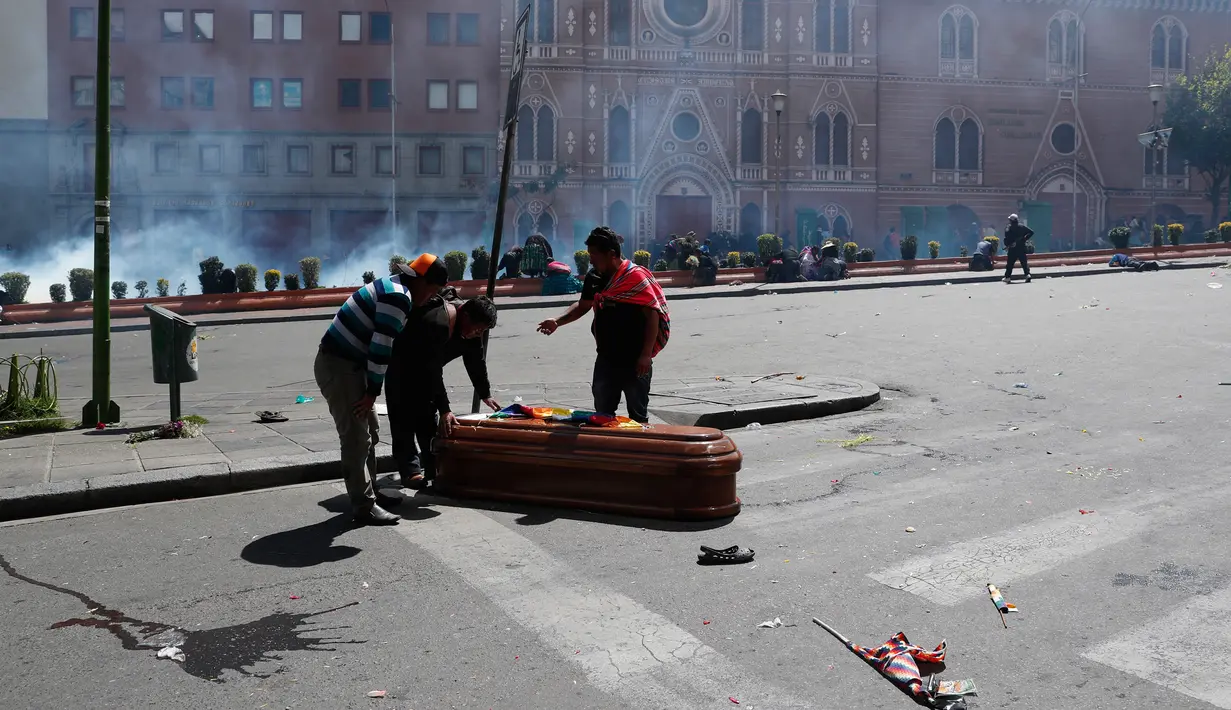 Peti mati berisi jenazah orang yang tewas dalam bentrokan antara pasukan keamanan dengan pendukung mantan Presiden Evo Morales tergeletak di tengah jalan setelah polisi meluncurkan gas air mata pada prosesi pemakaman besar-besaran di El Paz, Bolivia, Kamis (21/11/2019). (AP Photo/Juan Karita)