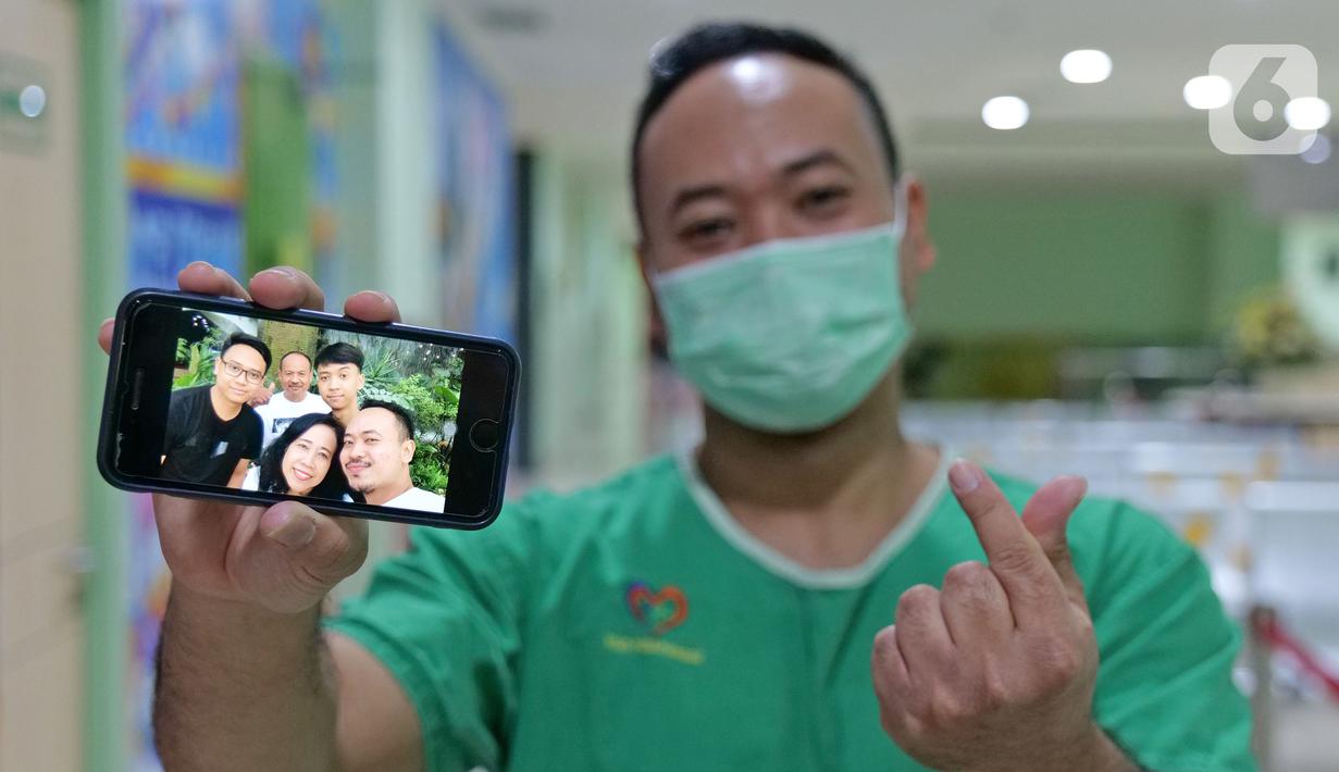 Petugas analis laboratorium Yosaphat Dimaz (28) menunjukkan foto keluarga saat di RSUD Pasar Minggu, Jakarta, Jumat (22/5/2020). Yosaphat Dimaz sudah 2,5 bulan tidak bertemu keluarga selama bertugas menjaga COVID-19 di RSUD Pasar Minggu. (Liputan6.com/Herman Zakharia)