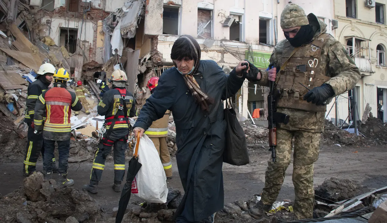 Relawan Pasukan Pertahanan Teritorial Ukraina membantu seorang perempuan menyeberang jalan di Kharkiv, 16 Maret 2022. Invasi Rusia ke Ukraina memasuki hari ke-21. Berbagai upaya negosiasi menuju kompromi telah dilakukan demi menuju perdamaian di antara kedua belah pihak. (AP Photo/Andrew Marienko)